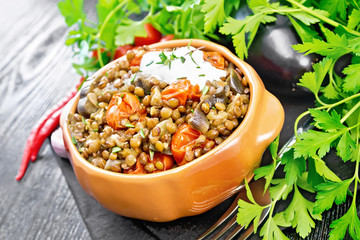 Lentils with eggplant and tomatoes in bowl on black board
