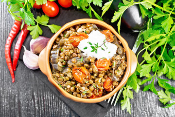 Lentils with eggplant and tomatoes in bowl on black board top