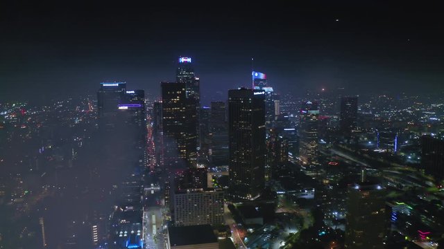 Downtown Los Angeles. Aerial panoramic view over the night cityscape. Colorful flashes of fireworks are seen over the city in the distance. Thick smoke from fireworks hides the scenery. 4K