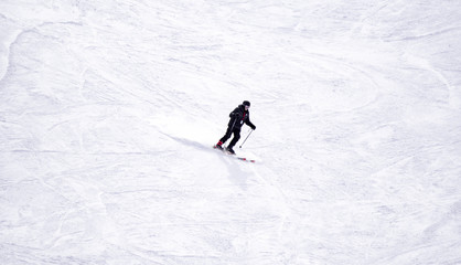 Full length of skier skiing on fresh powder snow. Man skier running downhill on sunny Alps slope