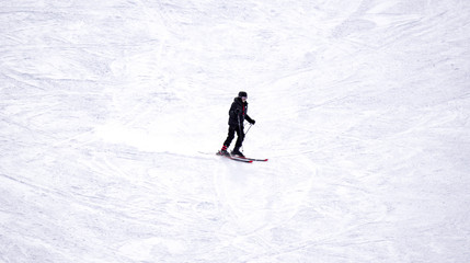 Fototapeta na wymiar Full length of skier skiing on fresh powder snow. Man skier running downhill on sunny Alps slope