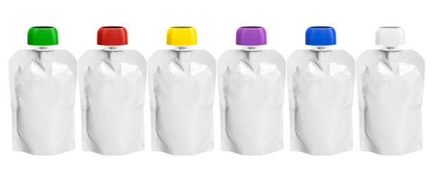 six White empty plastic doy pack with spout and round colored lid stand in line, for baby food, fruit puree, snack on the go, isolated on a white background