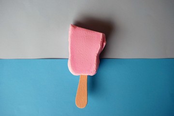 Broken pink ice cream on top of a blue background.