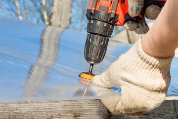 Power electric screwdriver. A man works with a hand-held power tool, close-up.