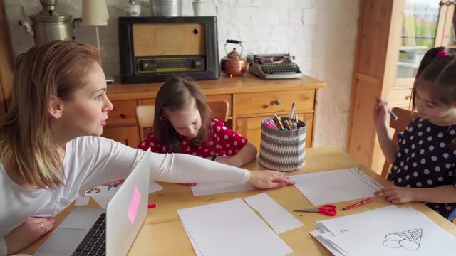 Childrens drawing on paper and mother works remotely during quarantine