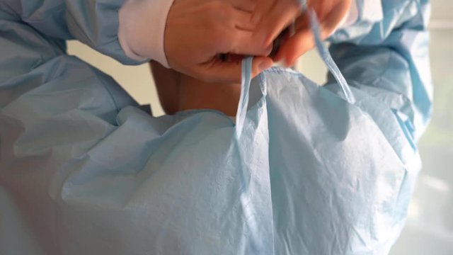 Female Doctor putting on her protective uniform