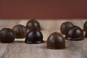Chocolate pralines on a wooden background stock images. Dark chocolate candies images. Chocolate...