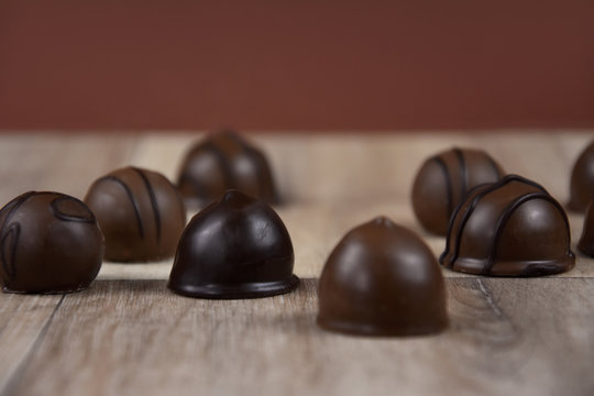 Chocolate pralines on a wooden background stock images. Dark chocolate candies images. Chocolate candies on the table stock images