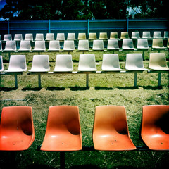Rows of plastic chairs outdoors at a sports oval