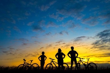 Naklejka na ściany i meble Action of cyclist and Bicycle silhouettes on the dark background of sunsets
