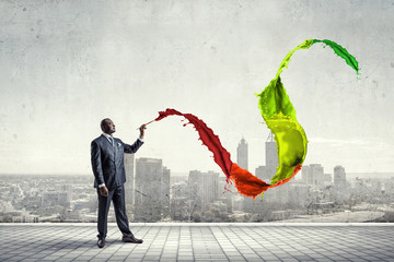 Conceptual image of ambitious and creative businessman in black suit holding paintbrush in hand