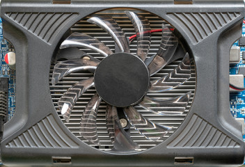 Black cooling fan of a computer graphics card, closeup top view.