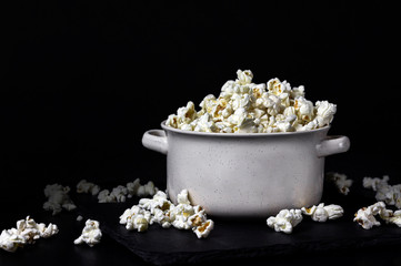 Popcorn in a white bowl on the black background. Copy space.