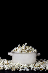 Popcorn in a white bowl on the black background. Copy space.