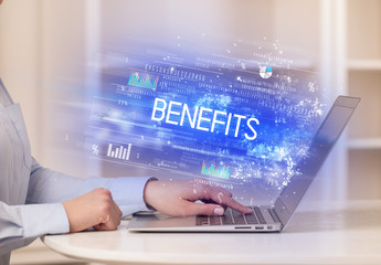 Closeup of businessman hands working on laptop with BENEFITS inscription, succesfull business concept