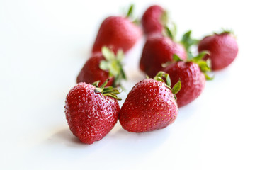 berries of ripe red strawberries laid out on a white background.
