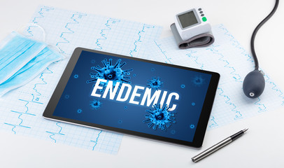 Tablet pc and doctor tools on white surface with ENDEMIC inscription, pandemic concept