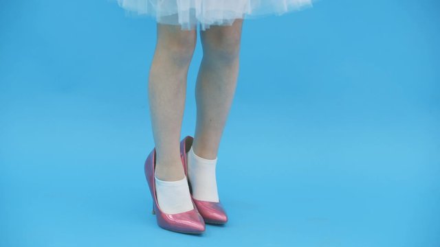 4k video where cute pretty little girl in high heels trying to keep balance wearing big mother's shoes.
