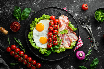 Breakfast. Fried eggs with bacon and cherry tomatoes. Top view. Free space for your text.
