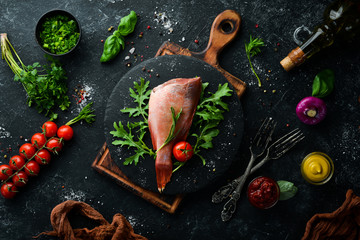 Raw sea red perch with rosemary and spices on a black plate. Seafood. Top view. Free space for your...