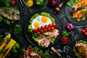 Food background. Set of dishes of fish, meat and vegetables on black stone background. Top view. Free copy space.