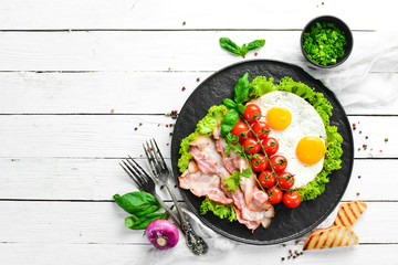 Breakfast. Fried eggs with bacon and cherry tomatoes. Top view. Free space for your text.