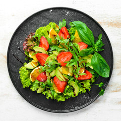 Healthy food: salad of arugula, avocado, strawberry and orange. Top view. Free space for your text.