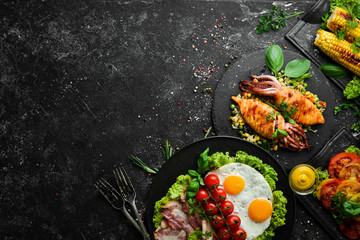 Food background. Set of dishes of fish, meat and vegetables on black stone background. Top view. Free copy space.