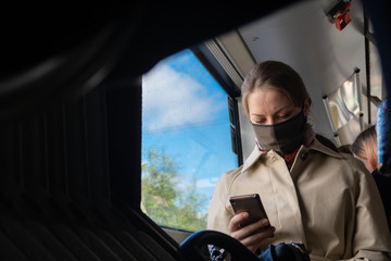 Vilnius, Lithuania - May 16 2020: Beautiful girl or woman with mask checking the app Stop Covid on...