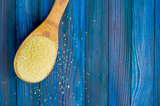 Spoon with porridge of cous cous. Useful vegetarian breakfast. Blue wooden background.