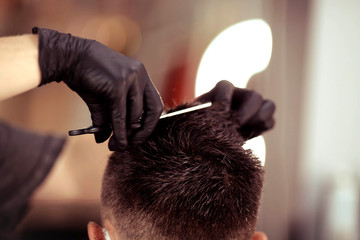 Hairdresser with security measures for Covid-19, holds scissors in his hands and cuts a man, social...
