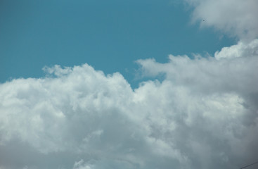 Fluffy clouds cover the summer blue sky