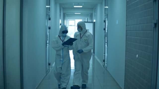 People walk in hospital, wearing protective suits during pandemic.
