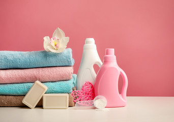 Obraz na płótnie Canvas Stack of bath towels with orchid flower, detergents, washing powder, soap on pink background