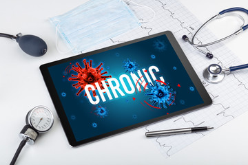 Tablet pc and doctor tools on white surface with CHRONIC inscription, pandemic concept