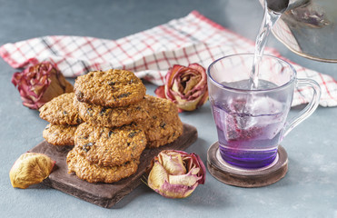Oatmeal cookies with prunes next to pink tea and rosescookies with prunes next to pink tea and roses