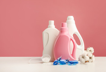 Fototapeta na wymiar Detergents, washing powder, washing capsules and cotton branch on pink background