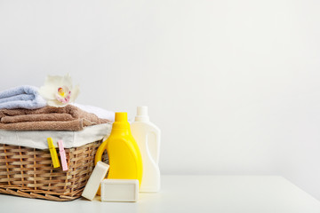 Wicker laundry basket with towels and white orchid flower, detergents and soap on white background