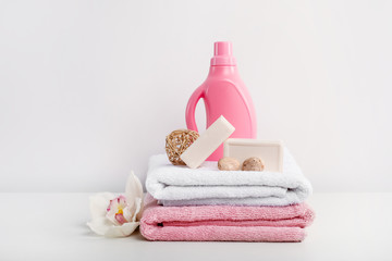 Stack of bath towels, detergent in rose bottle, soap and orchid flower on white background