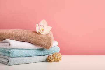 Stack of bath towels with white orchid flower on pink background