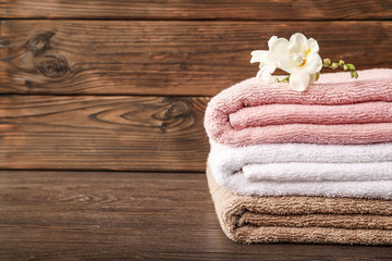 Obraz na płótnie Canvas Stack of bath towels with freesia flower on wooden background