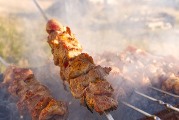 Cooking marinated shashlik on metal skewer on the grill. Backyard party background. cooking pork on skewers. BBQ on charcoal
