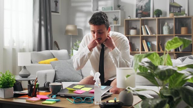 A young man works at home with a laptop without pants, during quarantine. Living room as an office.
