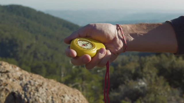 Traveler using compass navigating in mountain area