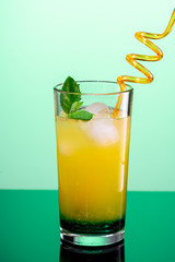cocktail of orange juice, mint syrup and ice in a direct glass on a blue background
