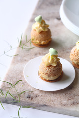 Contemporary key lime choux buns with craquelin, dipped in white chocolate, decorated with whipped...