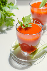 Tomato juice in a glass with celery and parsley leaves on white background. Lifestyle healthy eating concept 