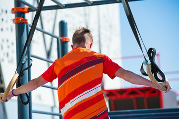Young man exercising on horizontal bar outdoors
