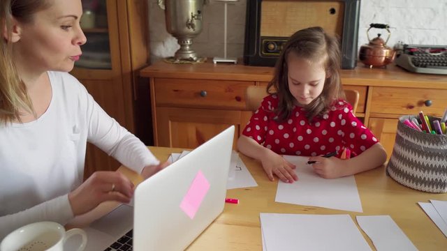 Childrens drawing on paper and mother works remotely during quarantine