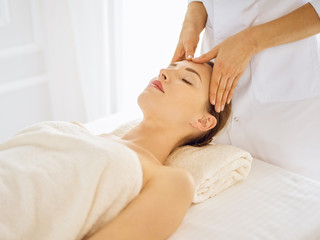 Fototapeta na wymiar Beautiful woman enjoying facial massage with closed eyes